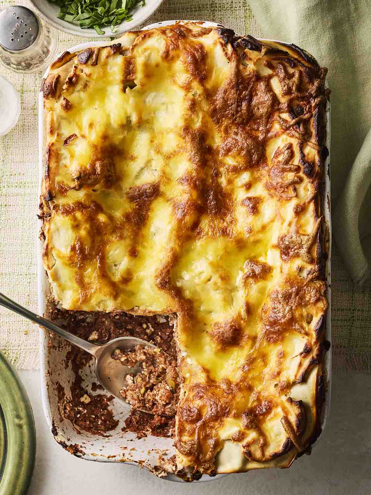 A golden-topped vegetarian lasagne with a spoon serving out the meal.