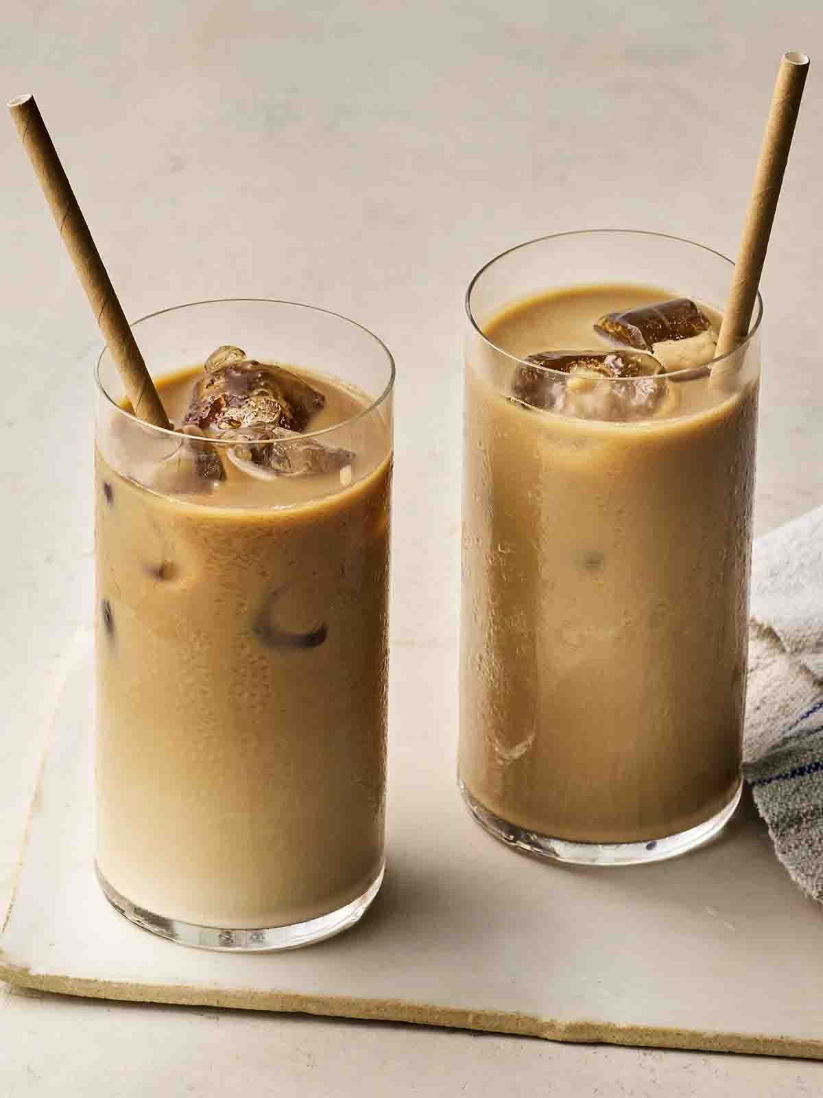 Two glasses filled with iced coffee, with straws, ready to drink.