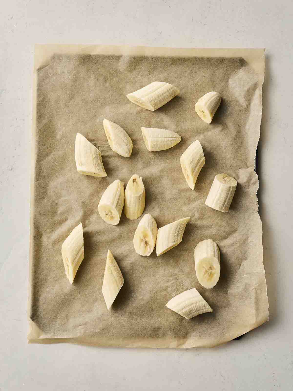 Chunks of banana on baking paper on a baking tray, ready to freeze.
