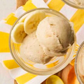 A dessert glass filled with banana frozen Nice Cream with a yellow and white napkin underneath.