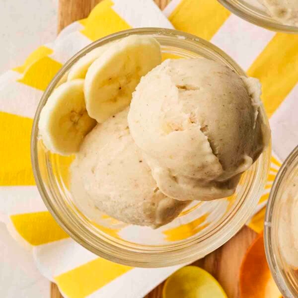 A dessert glass filled with banana frozen Nice Cream with a yellow and white napkin underneath.