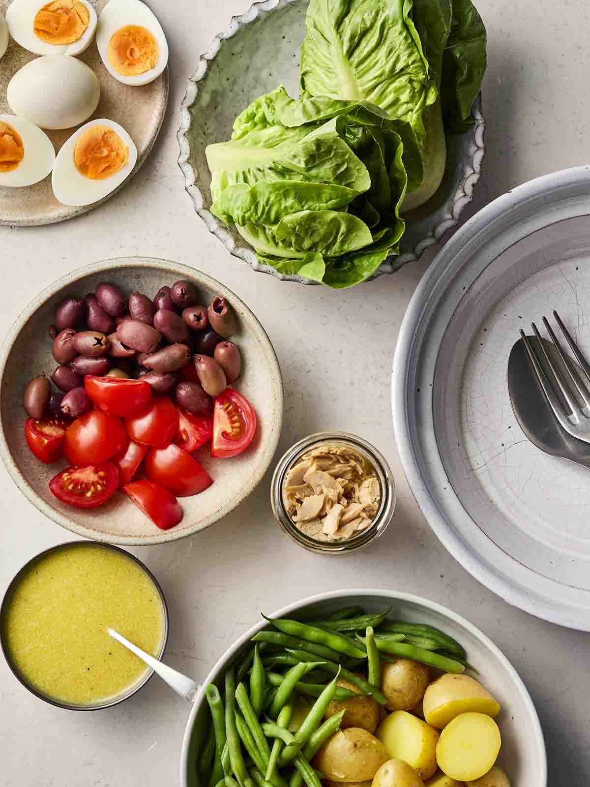 Plates of salad on a table, with eggs, olives, tomatoes.