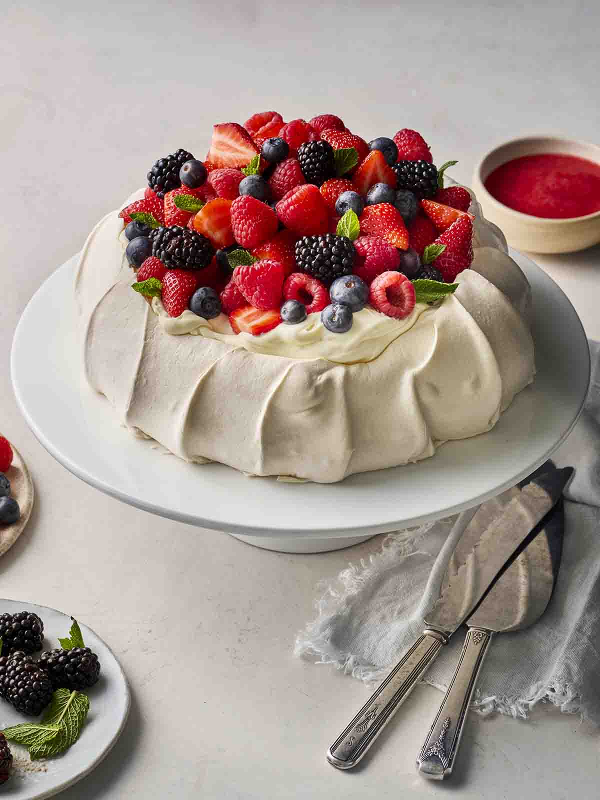 A summer dessert made with meringue, fruit and cream, ready to serve from a cake stand.