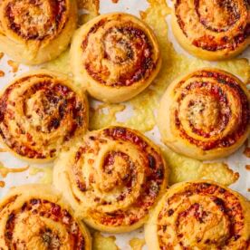 Eight just-baked Pizza Rolls on a baking tray, just out of the oven.