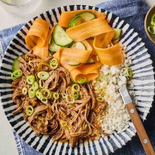 A close look at a placemat with a beef dish and rice and vegetables on a plate.