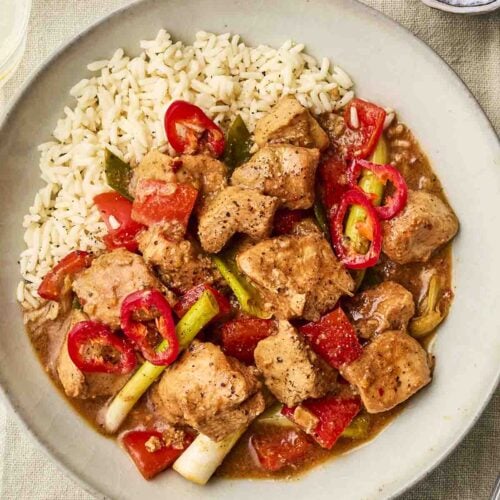 A plate of cooked food, including rice and a Chicken sauce dish.