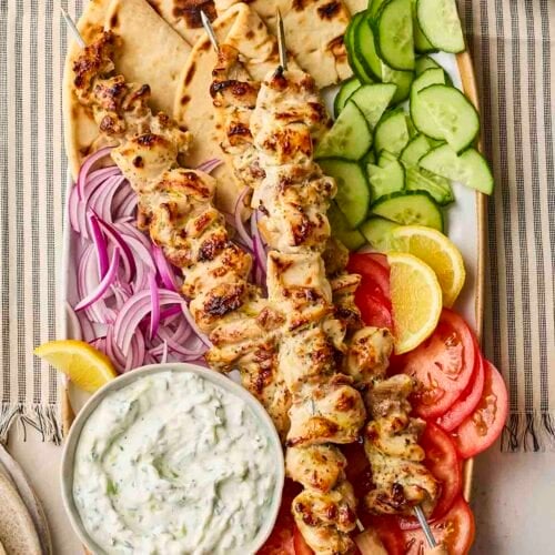 A plate filled with chicken souvlaki and side dishes.