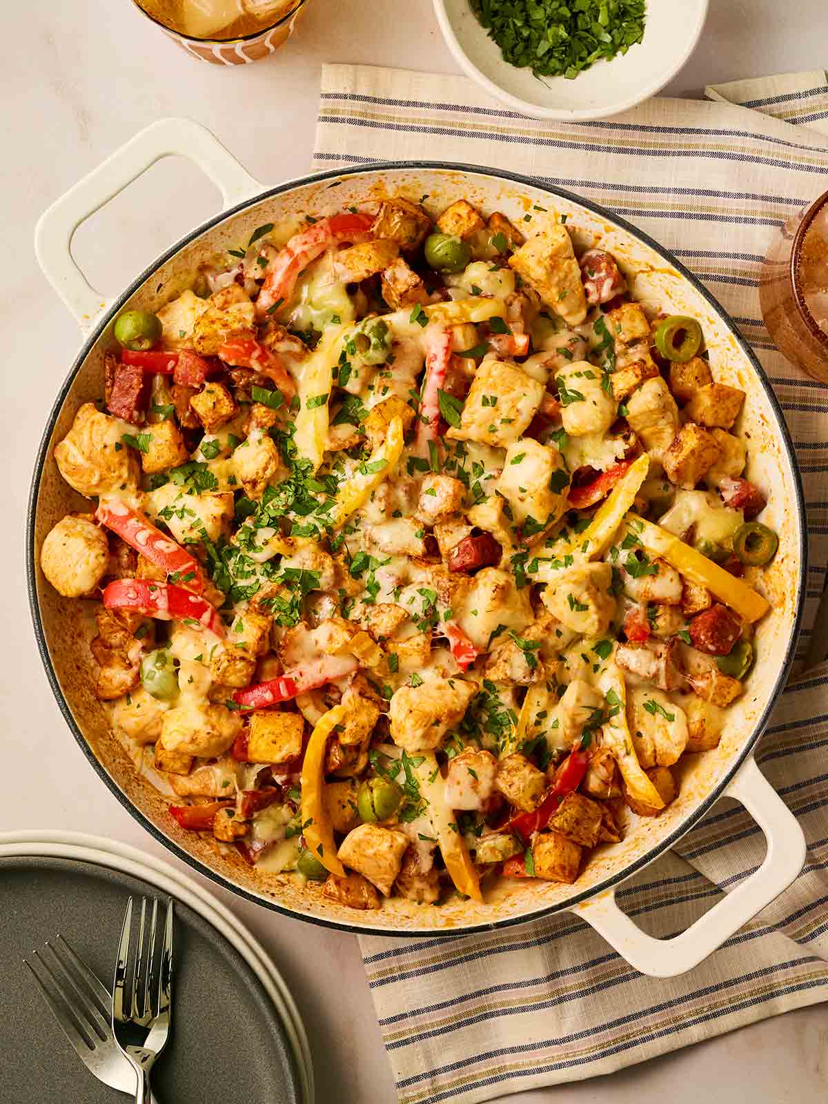 A pan of cooked loaded air fryer potatoes with chicken and chorizo, topped with melted cheese, on a table, ready to serve.