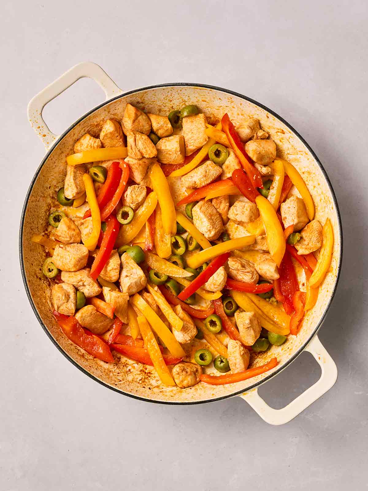 A pan filled with chicken and peppers and olives.