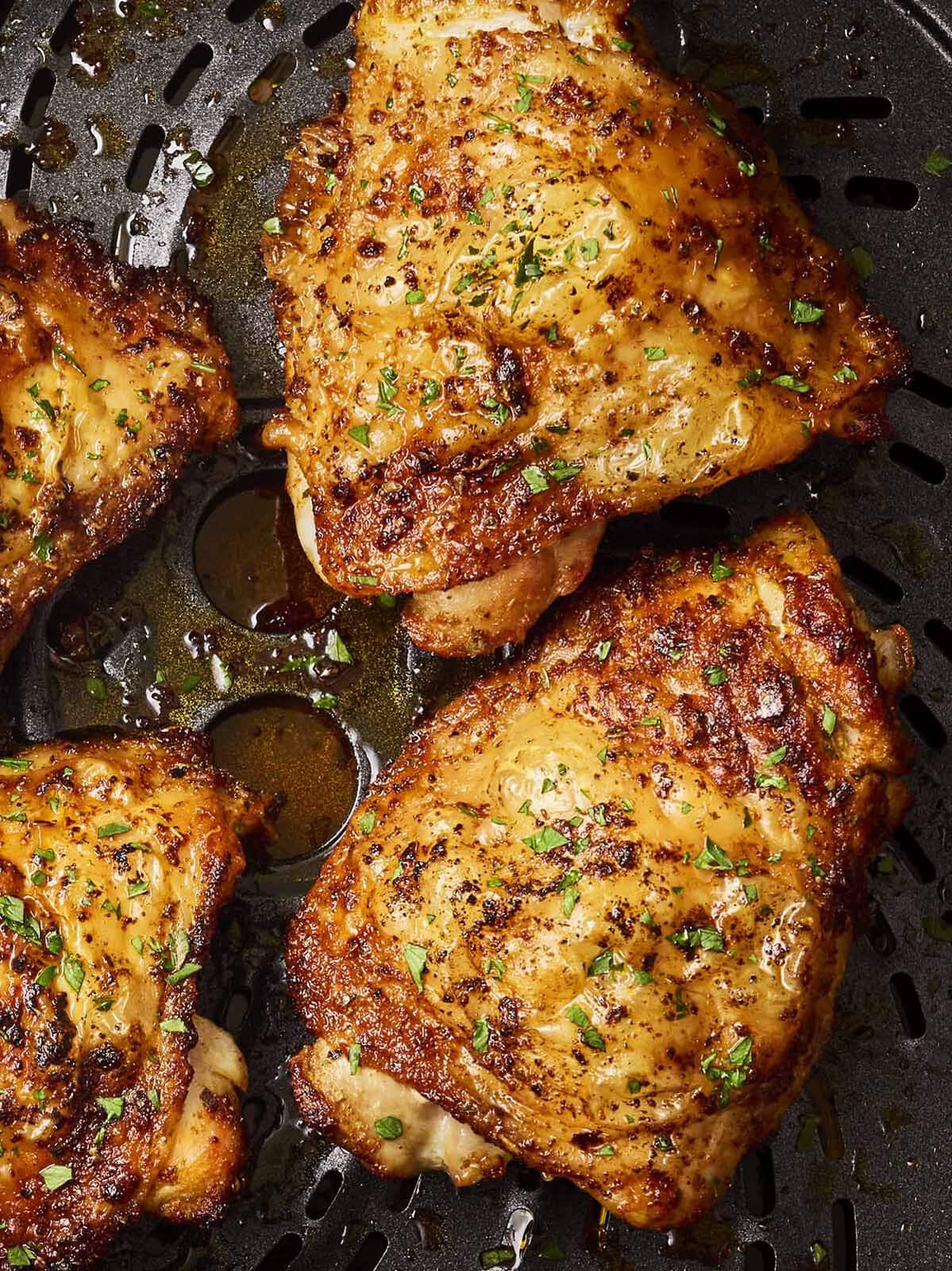 A close up of golden chicken thighs in a pan.