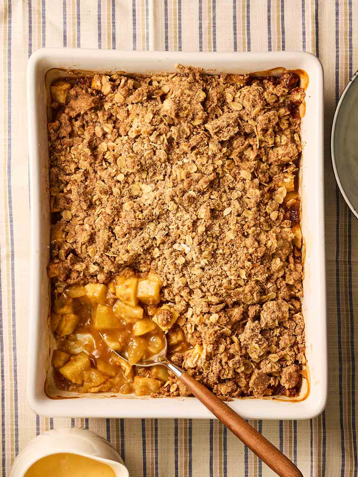 An apple crumble straight out of the oven, being served a portion from the corner.