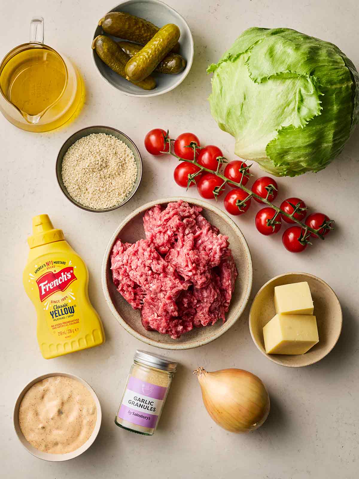 Ingredients laid out on a table, including beef mince, tomatoes, lettuce, mustard and more.