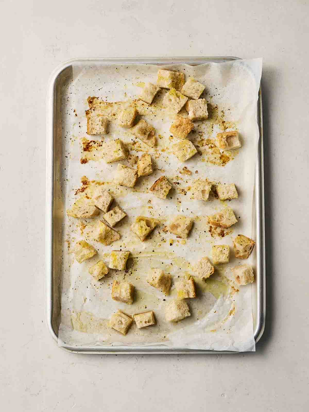 Chunks of bread on a baking tray, turned into croutons after being baked.