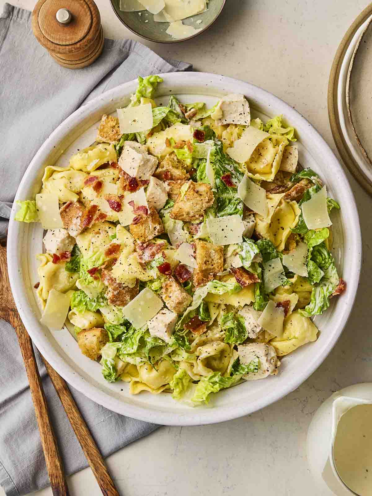 A bowl of chicken salad with creamy dressing, pasta and parmesan, on a plate on a set table.