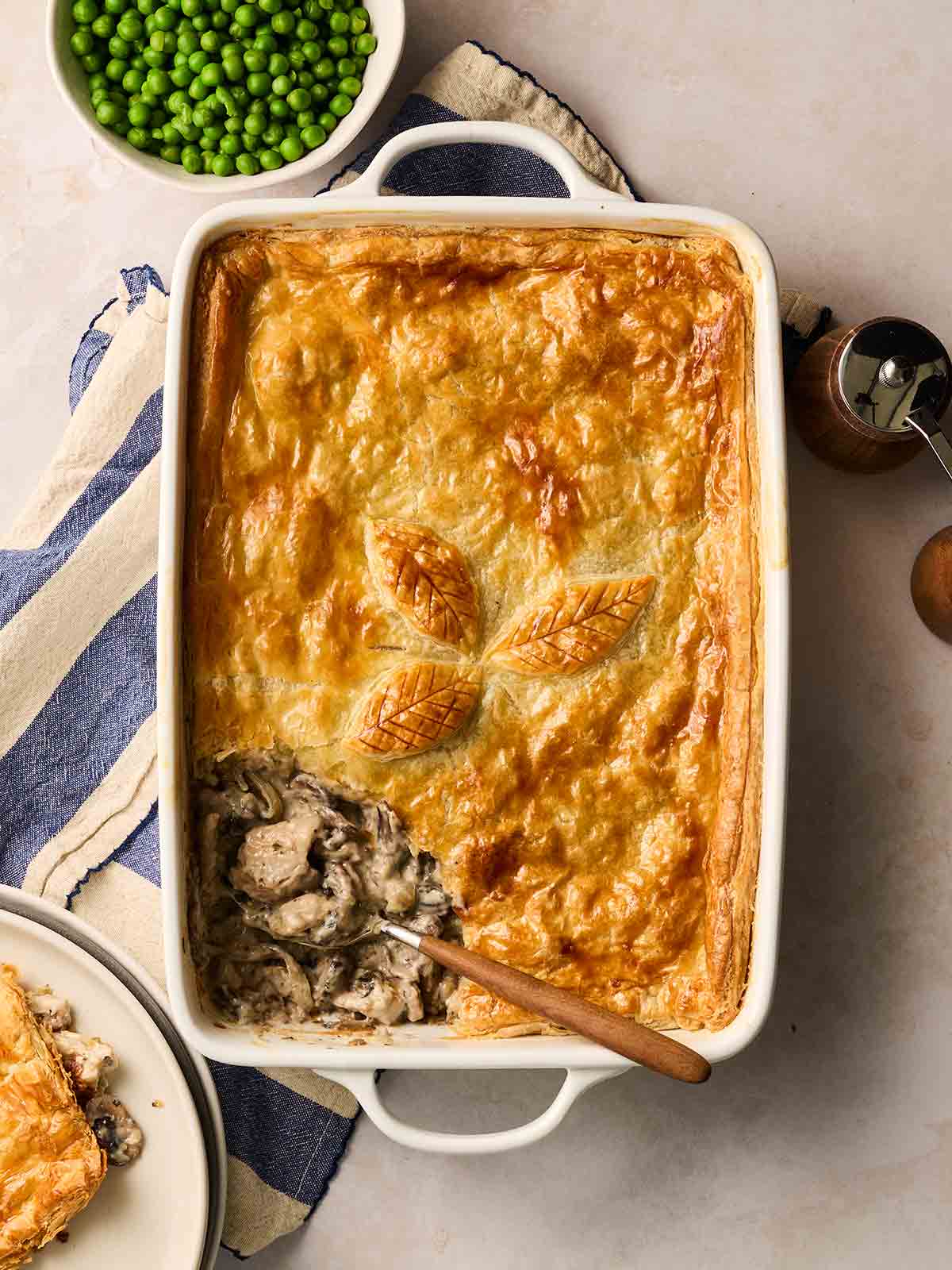 A Chicken and Mushroom Pie with golden pastry in a dish, being served up.