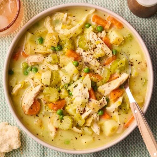 A table place set with a bowl of chicken soup, ready to eat.