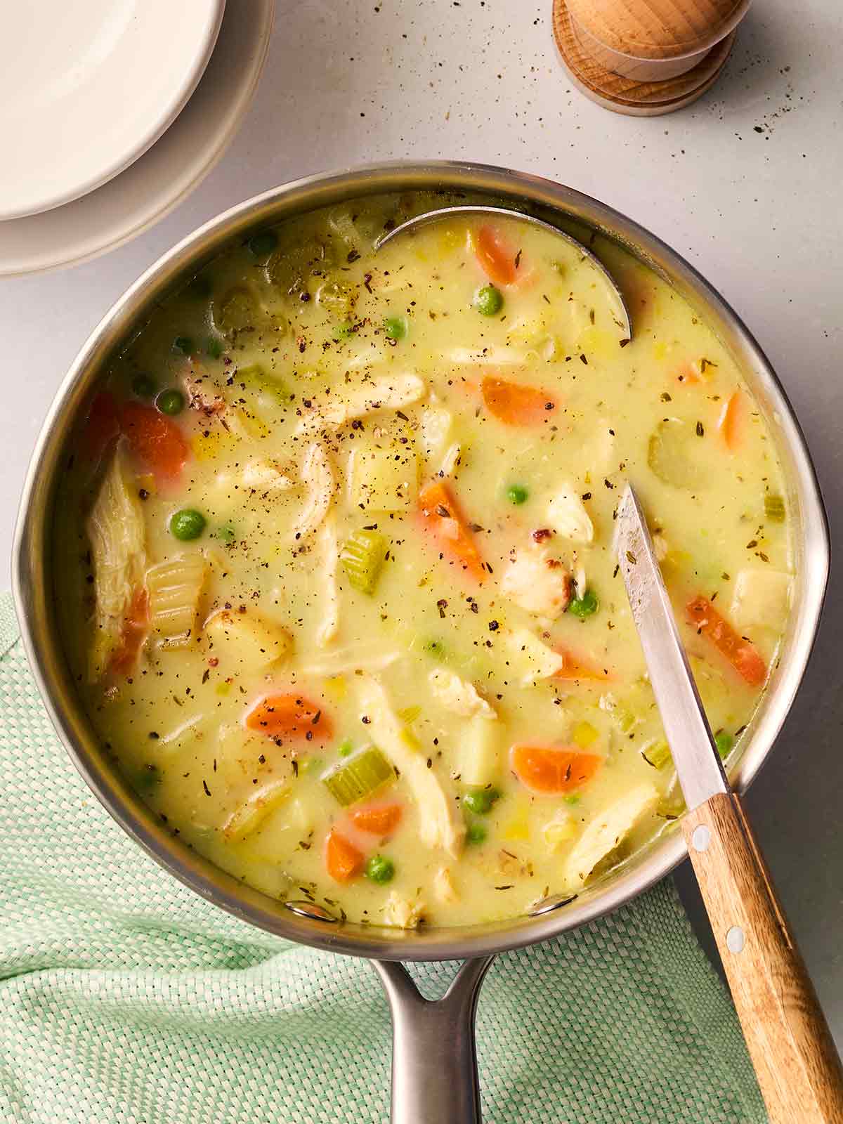 A pan with chicken soup inside, with a ladle inside ready to serve.