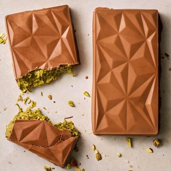 Two homemade bars of Dubai Chocolate side by side, one of them broken in the middle to show the green filing.