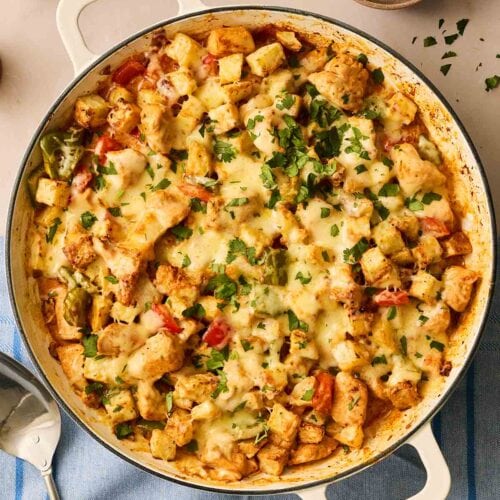 A large pan filled with Chicken Fajita sauce with potatoes made in an air fryer, with a bowl of coriander to the side.