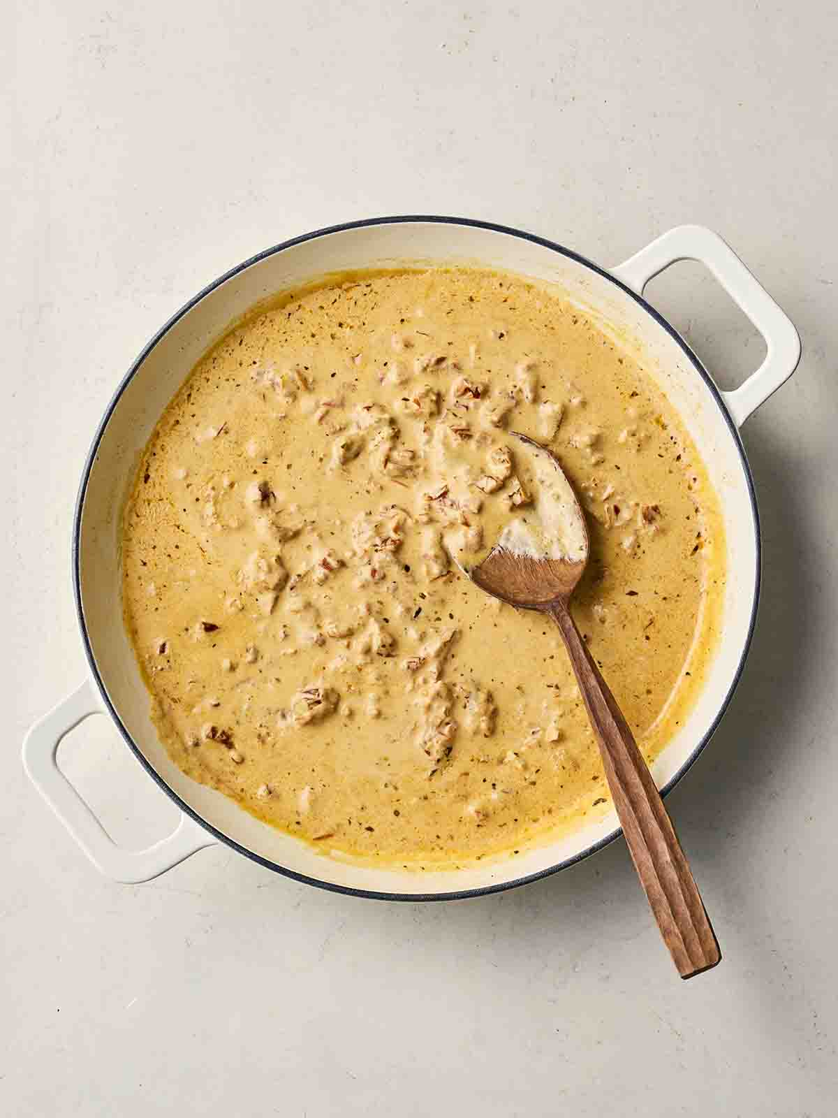 A pan filled with a creamy sauce with a spoon in.