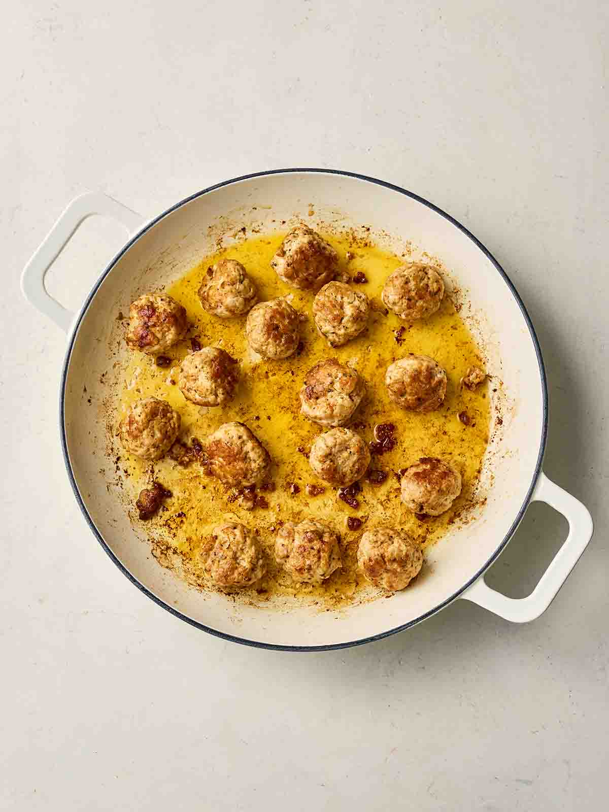 A white pan with frying chicken meatballs in.