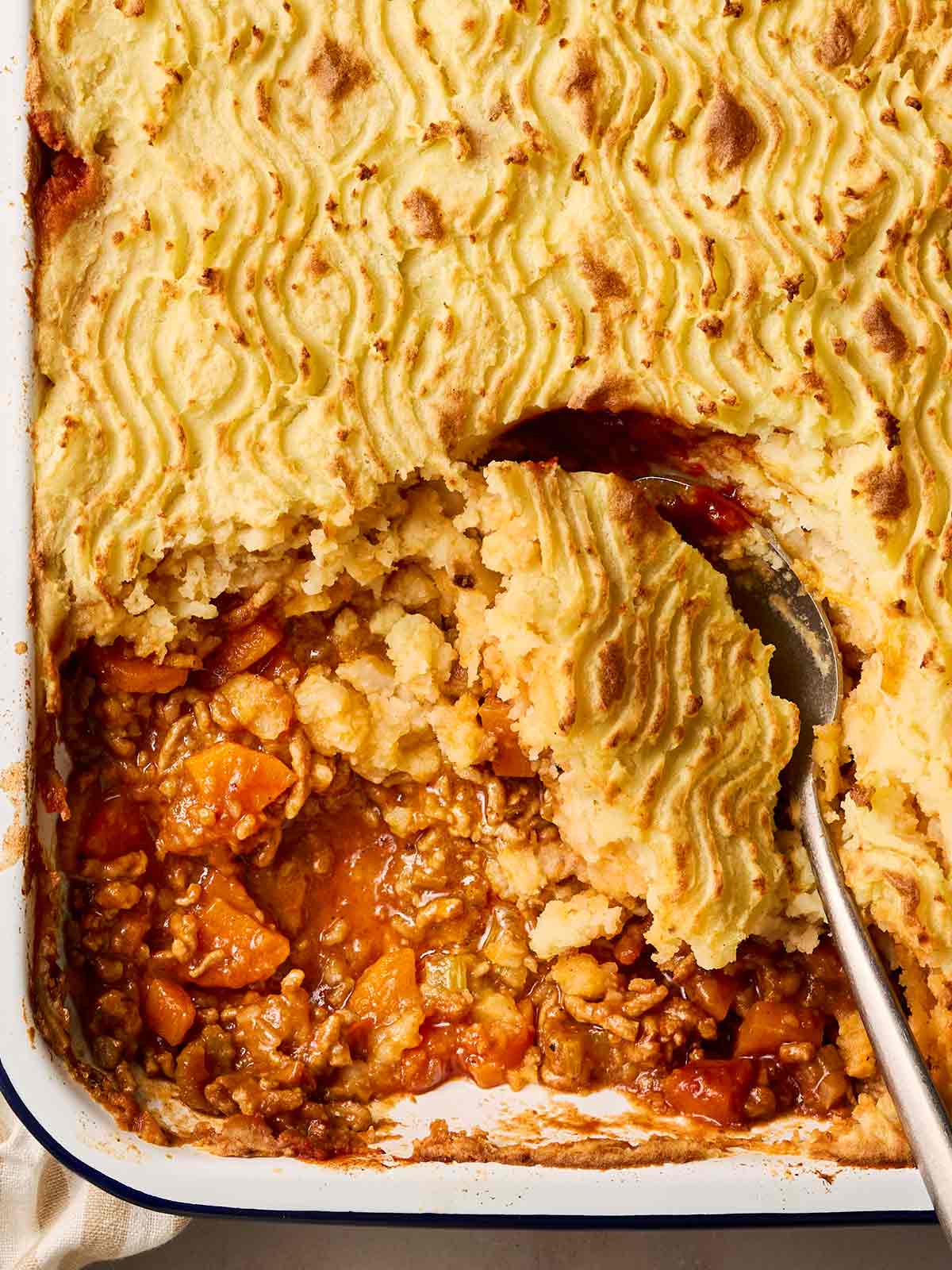 A close up of a classic shepherd's pie being served up with a spoon.