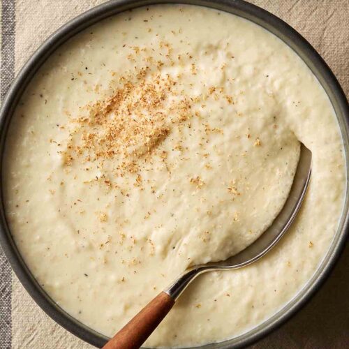 A bowl of bread sauce on a table cloth, ready to serve.