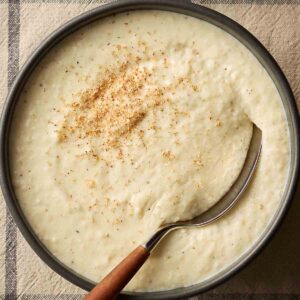 A bowl of homemade bread sauce with a spoon in to serve.