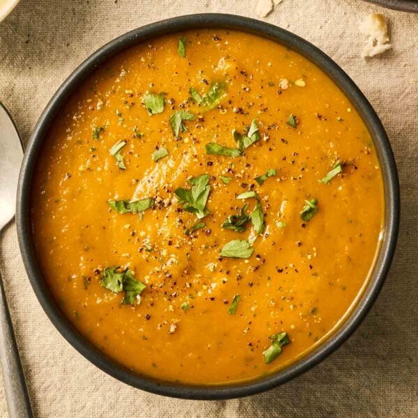 A close up of a bowl of orange Carrot and Coriander Soup.