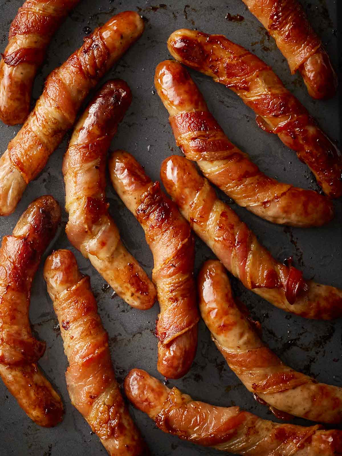 Pigs in Blankets on a black oven tray.