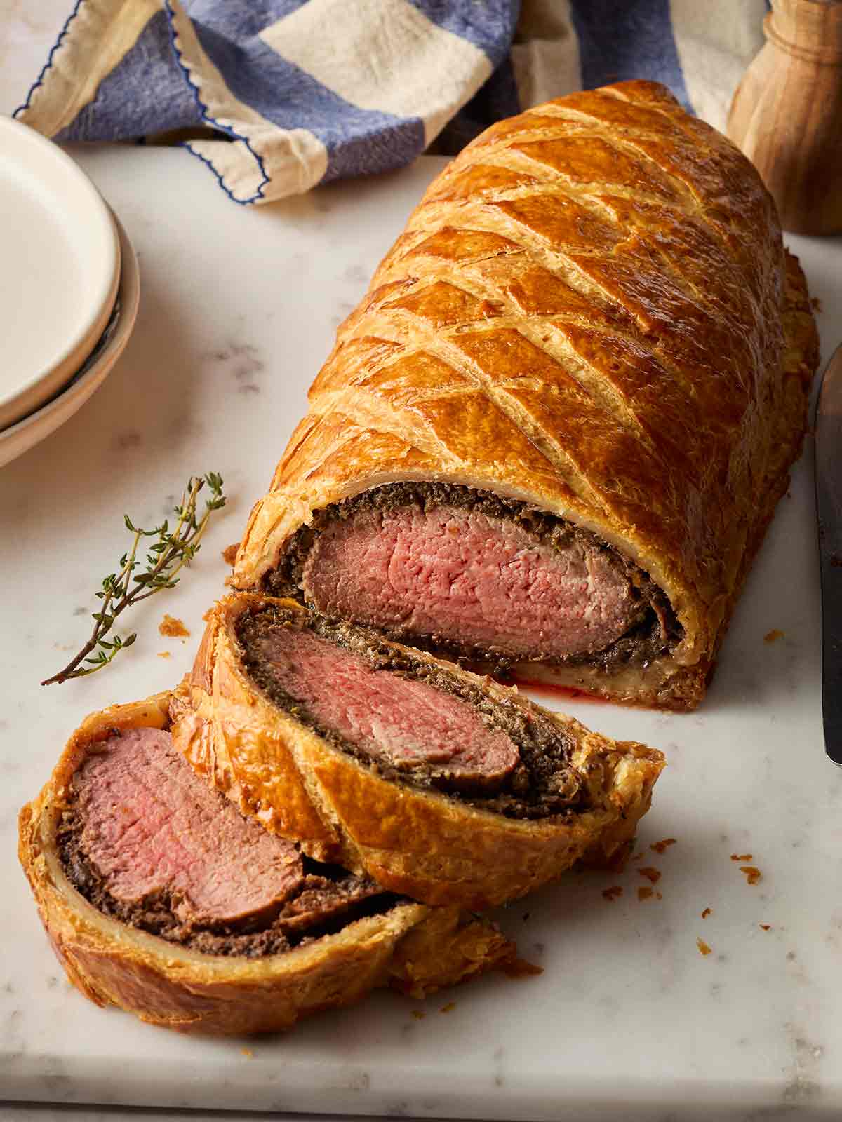 A side view of a classic Beef Wellington on a surface, ready to serve.
