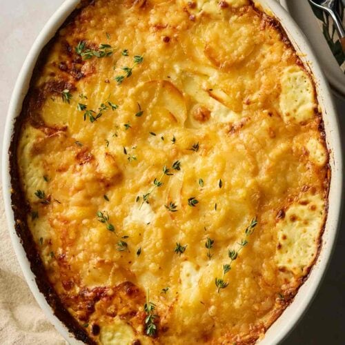 A dish filled with cheesy dauphinoise potatoes on a table, ready to be served.