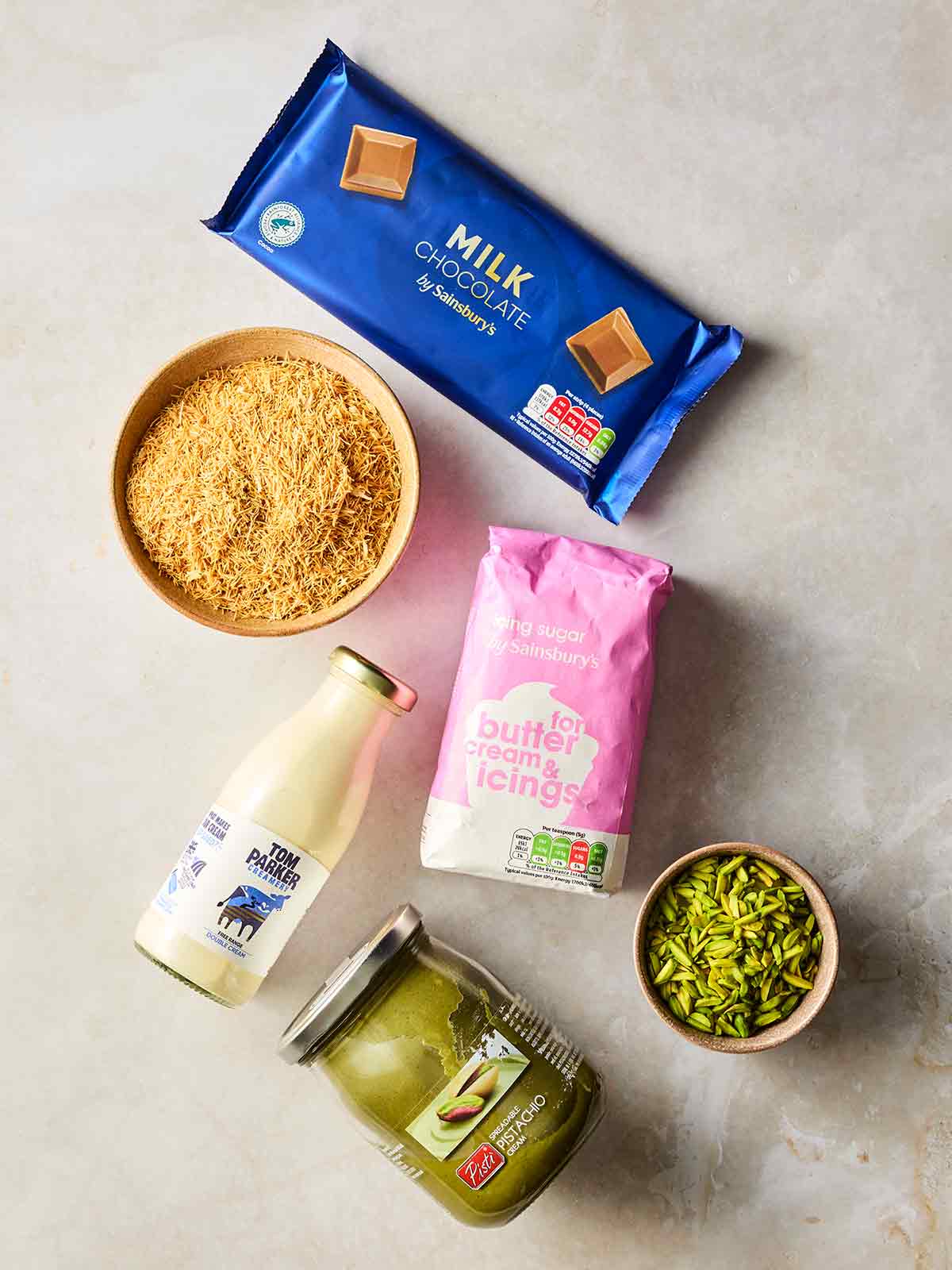 The ingredients for Dubai Chocolate Cheesecake laid out on a white counter top.