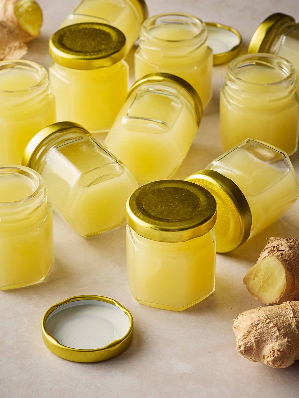 A surface with lots of small jars of ginger juice shots with lids on.