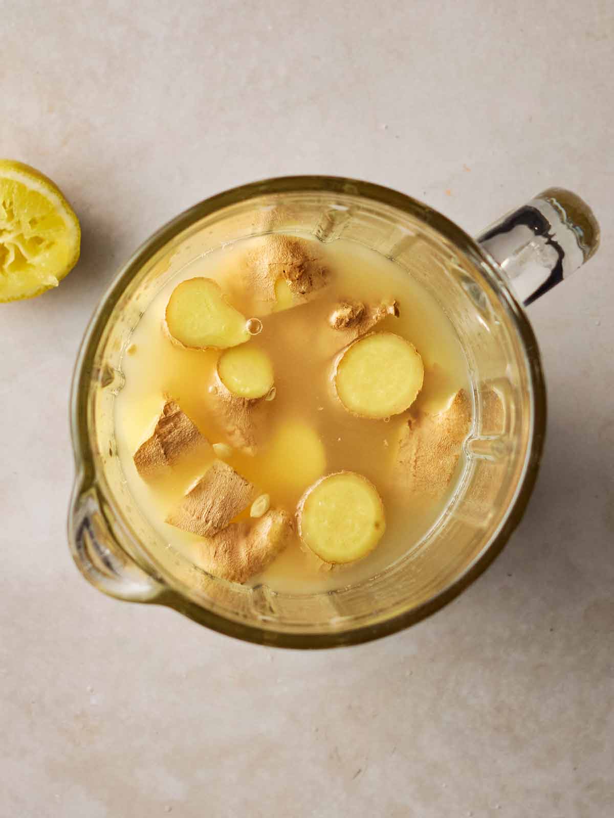 A jar filled with juice and chunks of fresh ginger.