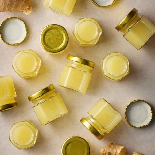 Small jars of ginger shots on a white counter.