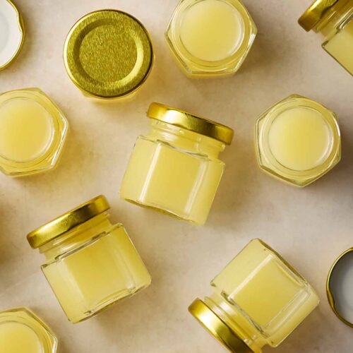 Lots of small jars of homemade ginger juice on a white surface.