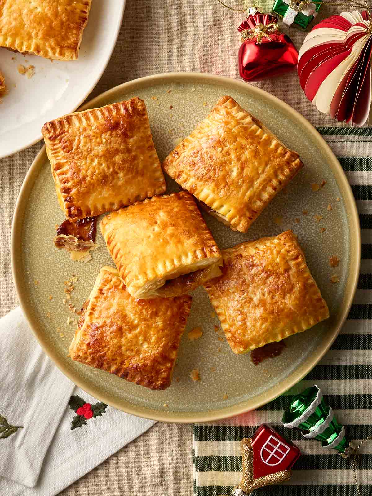 A Christmas table with a plate of square puff pastry mince pies on.