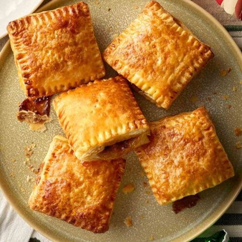 A plate of homemade mince pies on a table decorated for Christmas.