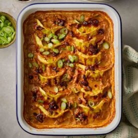 An oven dish with dumplings and vegetables in a red sauce on a table.