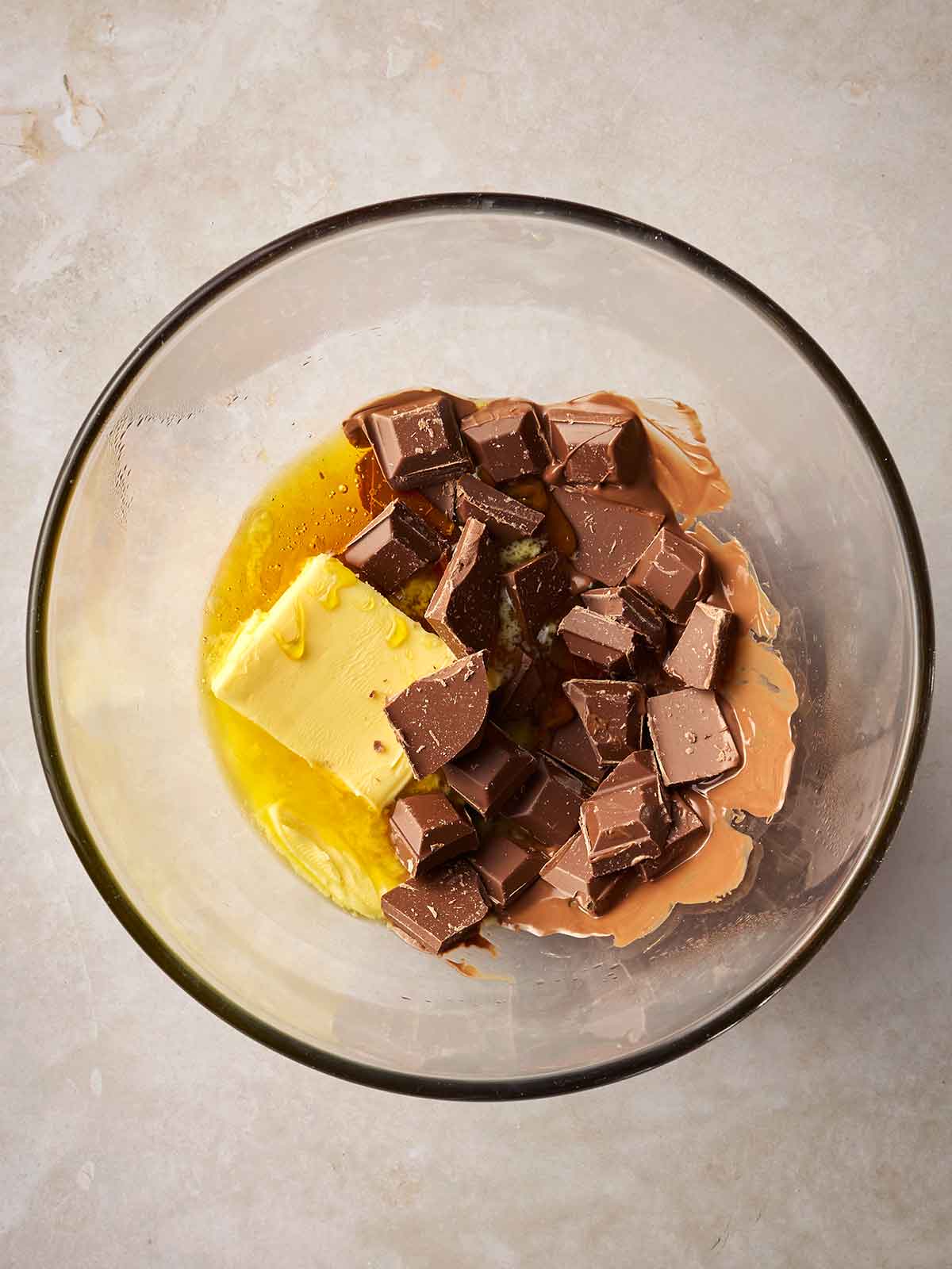 A glass bowl with half melted butter and chocolate inside for making rice crispy cakes.