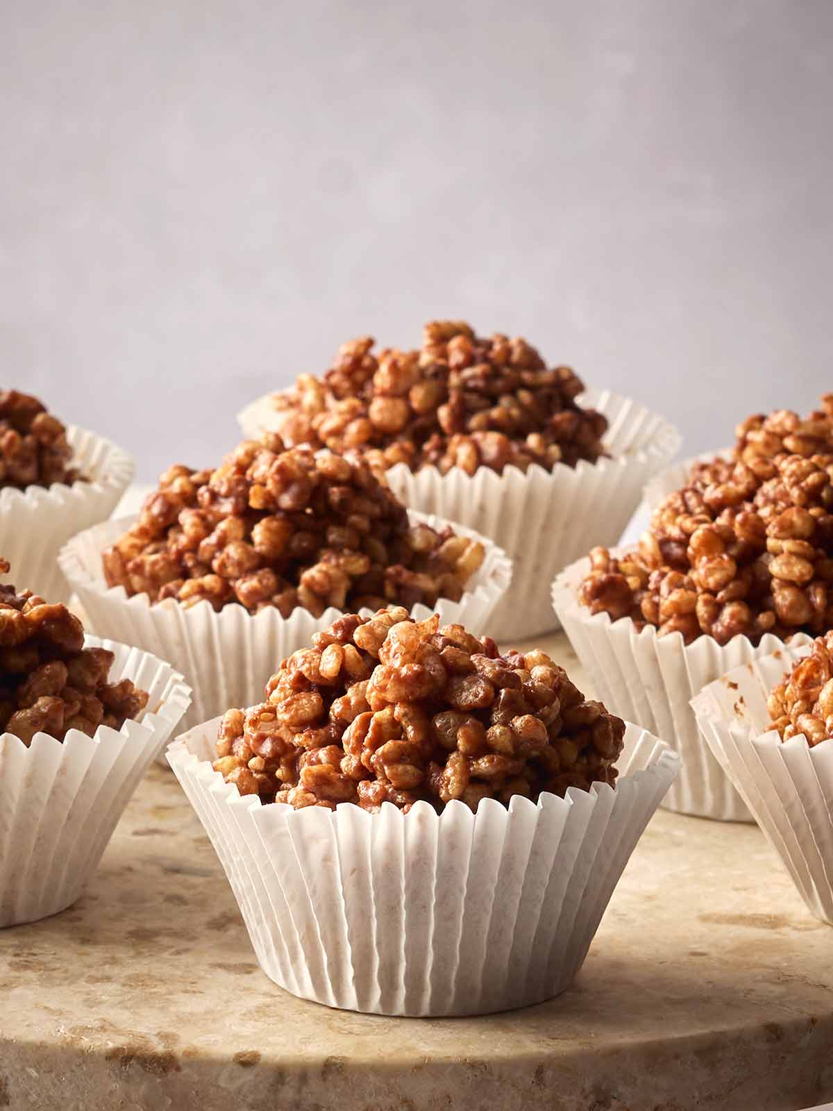 A side angle of rows of rice crispy cakes on a surface with a white background.