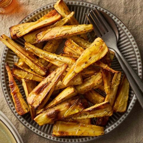 A plate on a table cloth with parsnips ready to eat.