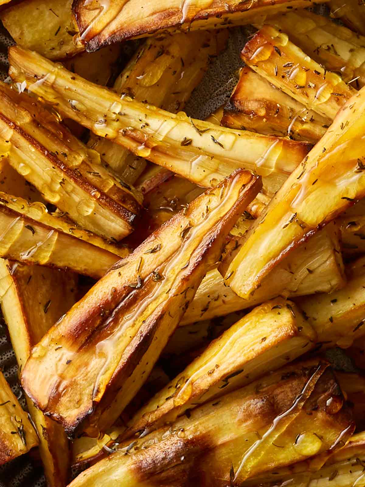 A close up of parsnips that have been roasted, drizzled with honey, oil and thyme.