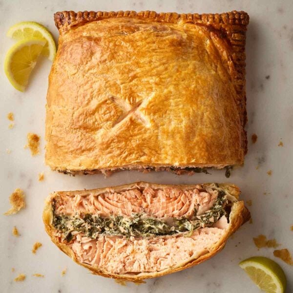 A top view of a cooked Salmon en Croute, with a slice on its side to reveal the filling.