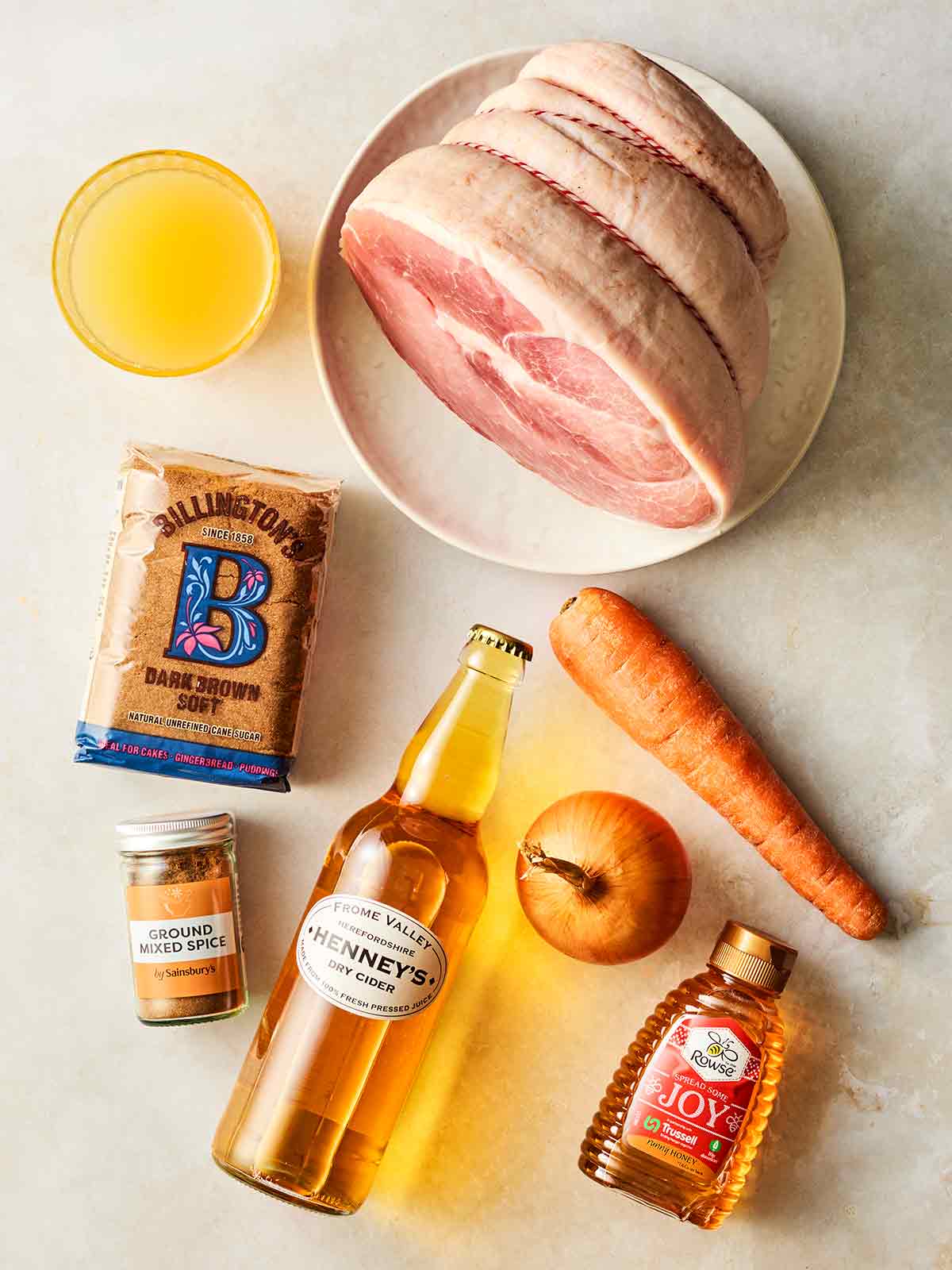 The ingredients for making a slow cooker ham on a white surface.