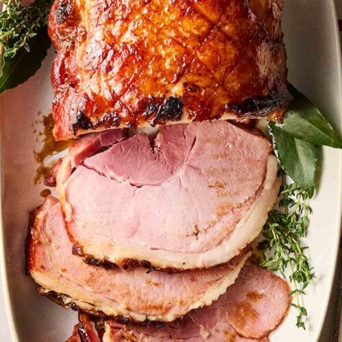 A sliced ham on a plate with a glazing on top.