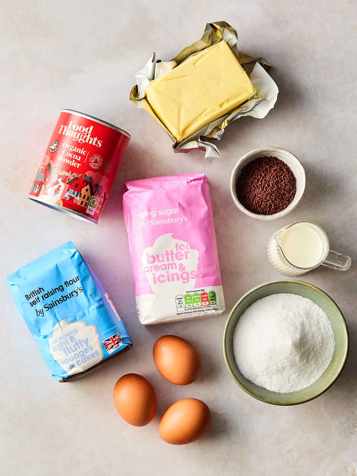The ingredients for making chocolate cupcakes laid out on a white counter.