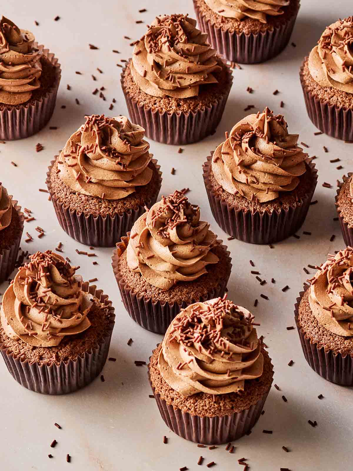 Easy Chocolate cupcakes with chocolate icing laid out on a white surface.