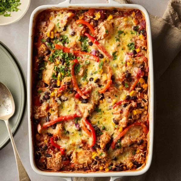 A one pot dinner in a serving dish on a table, with rice, chicken and mexican style veggies.